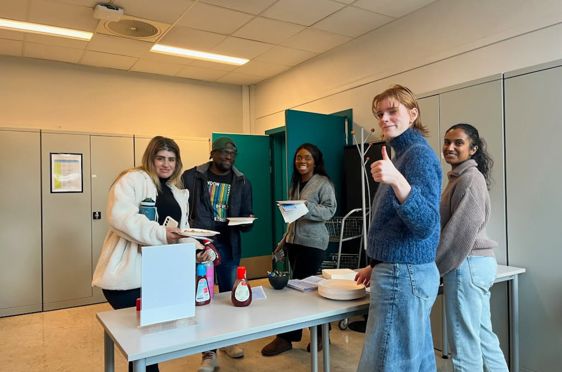 en gruppe personr som står rundt et bord med mat og drikke