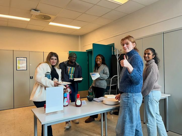 en gruppe personr som står rundt et bord med mat og drikke