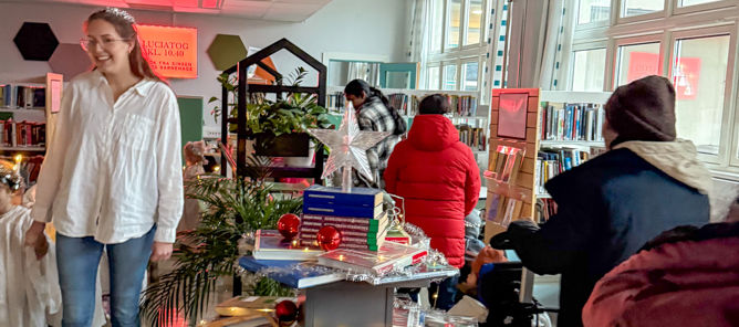 en gruppe mennesker i et rom med et bord med bøker på