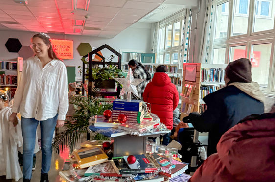 en gruppe mennesker i et rom med et bord med bøker på