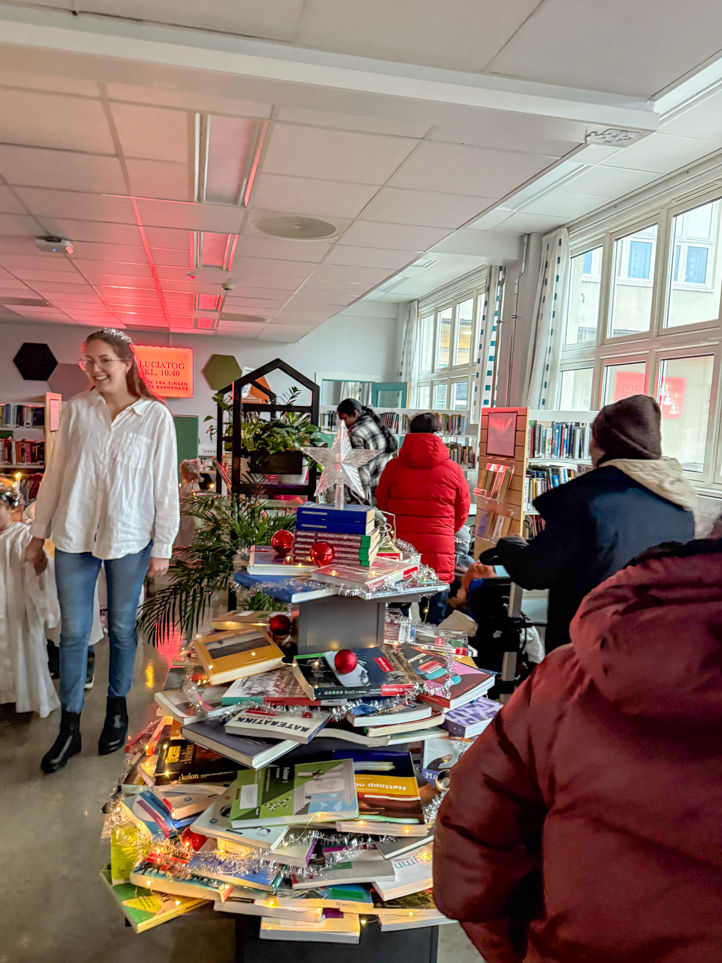 en gruppe mennesker i et rom med et bord med bøker på