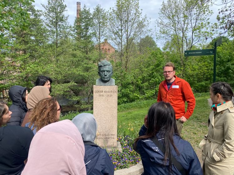 En gruppe elever som står rundt en statue