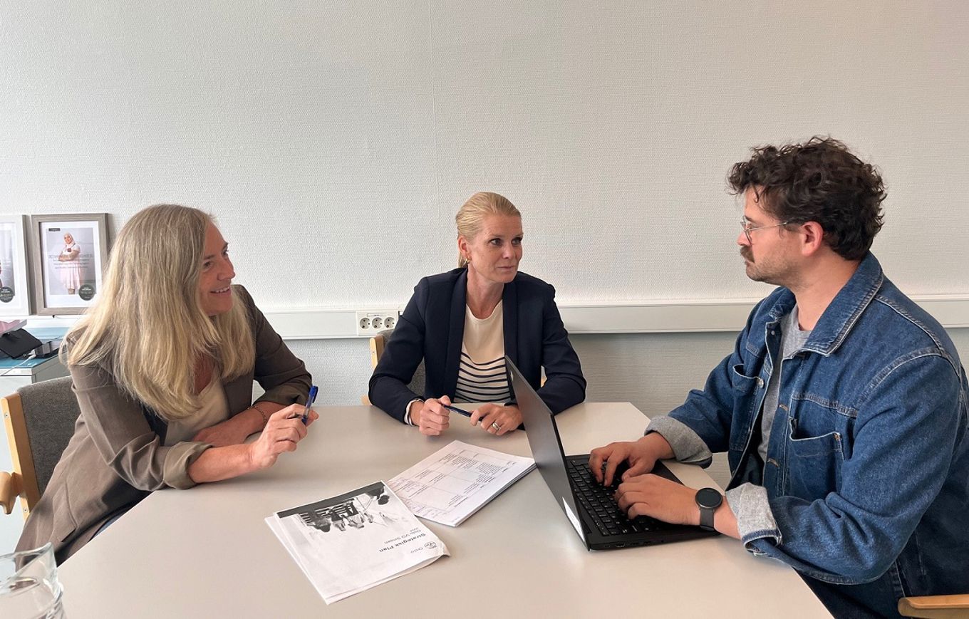 en gruppe mennesker som sitter rundt et bord og ser på en bærbar datamaskin